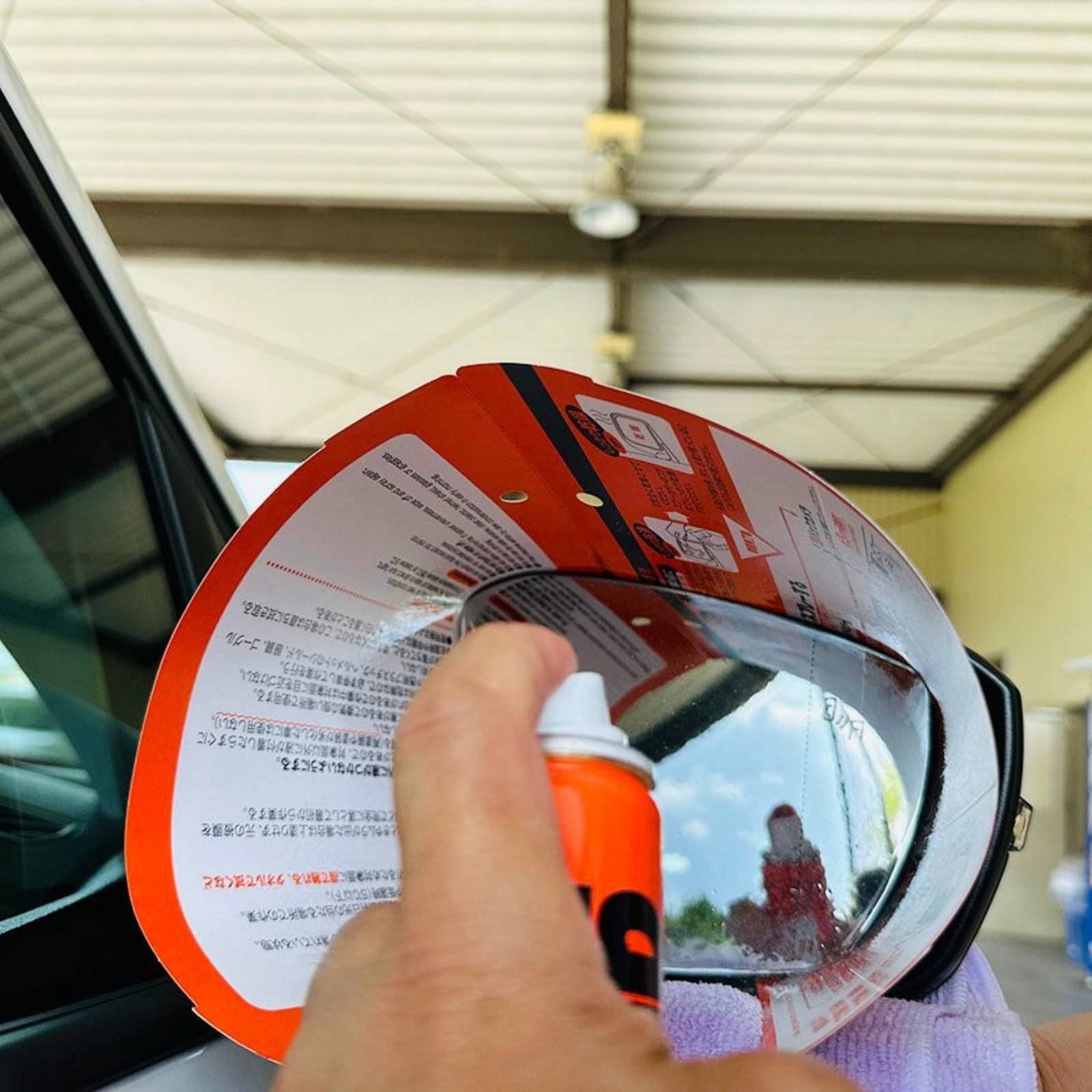 Applying Soft99 Glaco Mirror Coat Zero waterproof coating spray on car side mirror for rain protection